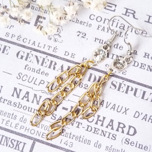 May include: Gold chain earrings with clear crystal accents. The earrings are hanging from silver hooks.