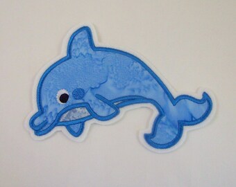 Könnte beinhalten: Ein blauer gestickter Delfin-Patch mit weißem Rand. Der Delfin hat ein weißes Auge mit schwarzer Pupille.