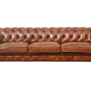 May include: A brown leather Chesterfield sofa with tufted buttons and rolled arms. The sofa has a classic design and is perfect for a traditional living room.