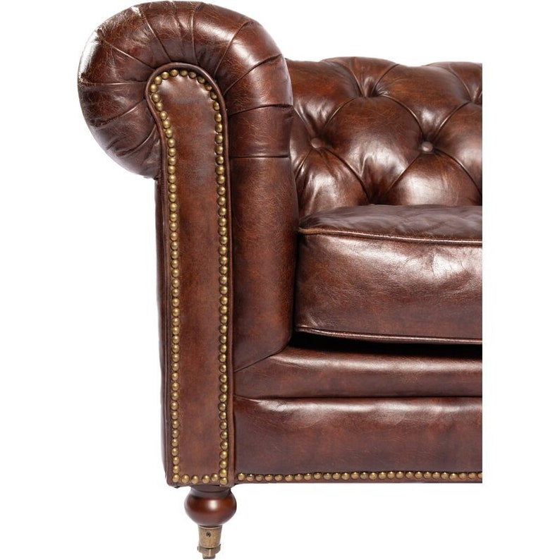 May include: A brown leather sofa with tufted upholstery and brass nailhead trim. The sofa has a rolled back and wooden legs.