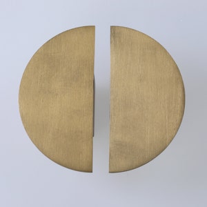 Op de afbeelding: Een paar halfronde deurgrepen van geborsteld messing.