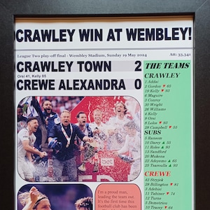 May include: Framed newspaper clipping announcing Crawley Town's victory at Wembley Stadium on May 19, 2024. The headline reads "CRAWLEY WIN AT WEMBLEY!" with the score 2-0. Includes team rosters and a quote from the Crawley manager.