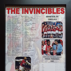 Op de afbeelding: Een ingelijste poster ter ere van het seizoen 2003/04 van Arsenal Football Club, ook wel bekend als "The Invincibles." De poster bevat een teamfoto, een tabel met wedstrijdresultaten en een lijst met de topscorers. De eindpositie van het team in de Barclay's Premier League wordt gemarkeerd als "1e."