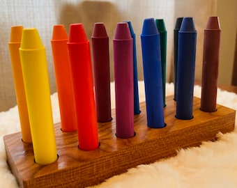 Könnte beinhalten: Ein Holzhalter mit 12 bunten Buntstiften, darunter rot, orange, gelb, grün, blau, lila und braun.