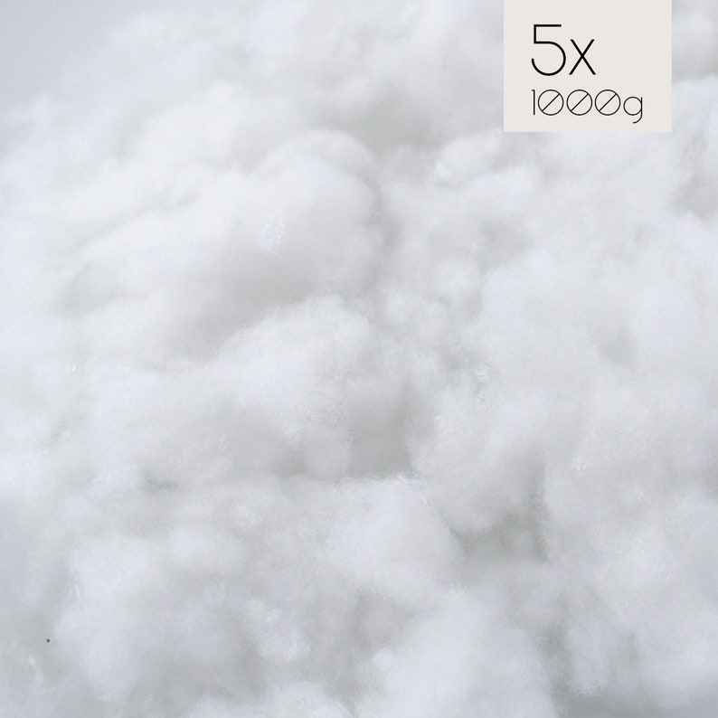 May include: A close-up of a large amount of white fluffy stuffing. The text "5x 1000g" is visible in the upper right corner of the image.