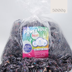 Puede incluir: Una gran bolsa de plástico transparente llena de retazos de tela coloridos. Una etiqueta en la bolsa dice "POWER FÜLL bunt" y "5000g". La etiqueta también incluye texto en alemán y una ilustración de oso de dibujos animados.