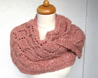 May include: A pink knitted infinity scarf with a delicate lace pattern. The scarf is draped over a wooden mannequin.