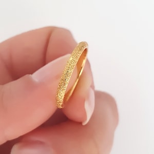 Könnte beinhalten: Ein dünner Goldring mit einer strukturierten Oberfläche.