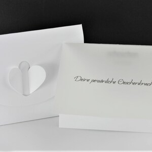 Puede incluir: Sobre blanco con un recorte en forma de coraz&oacute;n y una tarjeta blanca con el texto "Deine pers&ouml;nliche Geschenkernachricht" en negro.