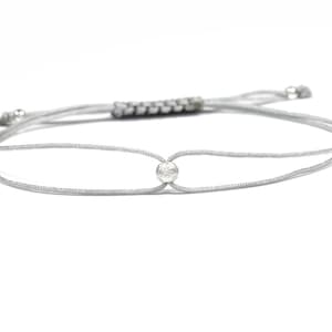 Könnte beinhalten: Ein silbernes Armband mit einer einzigen kleinen, runden silbernen Perle in der Mitte.