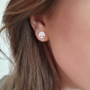 Könnte beinhalten: Ein Paar silberne Ohrstecker mit einem Lebensbaum-Motiv.