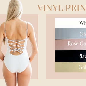 Op de afbeelding: Witte badpak met een veterdetail op de rug. Vinyl-drukopties omvatten wit, zilver, ros&eacute; goud, zwart en goud.