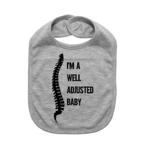 May include: Gray baby bib with a black spine graphic and the text "I'm a well adjusted baby".