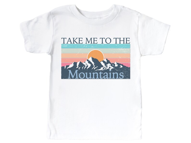 May include: White t-shirt with a vintage-style graphic of a mountain range with a setting sun and the text "Take Me To The Mountains".