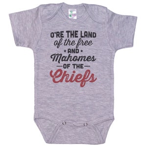 Pode incluir: Macac&atilde;o de beb&ecirc; cinza com o texto "O're the land of the free and Mahomes -of the- Chiefs" em preto e vermelho.