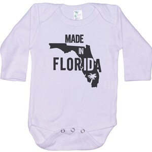 K&ouml;nnte beinhalten: Wei&szlig;er Langarm-Babybody mit schwarzem Text "Made in Florida" und einer schwarzen Umrandung des Bundesstaates Florida mit einer Palme.
