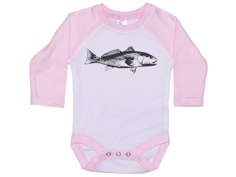 May include: A white baby onesie with pink sleeves and a black and white illustration of a fish on the front. The onesie has three white snaps at the bottom.
