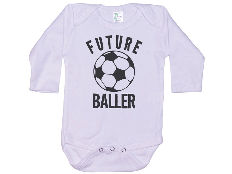 May include: White long-sleeve baby onesie with black text that reads "FUTURE BALLER" and a black and white soccer ball graphic.