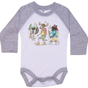 May include: A white long-sleeve baby bodysuit with a grey raglan sleeve design. The bodysuit features a cartoon illustration of a moose, a raccoon, and a bear wearing backpacks and hiking in the woods.