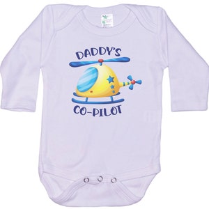 May include: White long-sleeve baby onesie with a blue and yellow helicopter graphic and the text "Daddy's Co-Pilot".