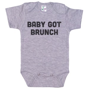 May include: A gray baby onesie with the text "BABY GOT BRUNCH" printed in black.