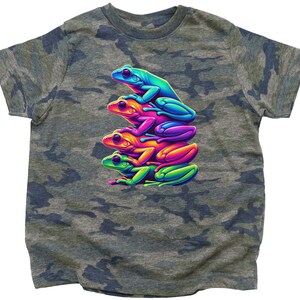 May include: A camouflage t-shirt with a graphic of four stacked frogs in rainbow colors. The frogs are facing to the right and are stacked on top of each other.