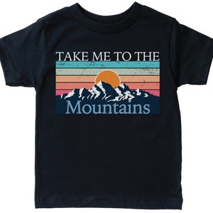 May include: A black t-shirt with a vintage-style graphic of mountains and a sunset. The text "Take Me To The Mountains" is printed on the shirt.