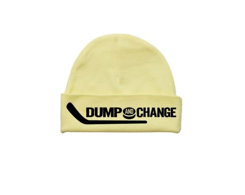 May include: A yellow beanie with a black hockey stick and puck graphic and the text "DUMP AND CHANGE".