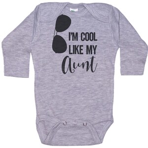 May include: Gray long-sleeve baby bodysuit with black text that reads "I'm cool like my aunt" and a pair of sunglasses graphic.