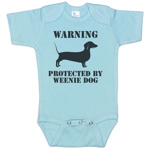 May include: Light blue baby onesie with a black dachshund silhouette and the text "WARNING PROTECTED BY WEENIE DOG".