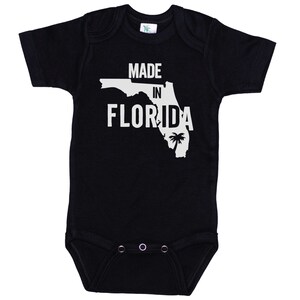 K&ouml;nnte beinhalten: Schwarzer Baby-Strampler mit wei&szlig;em Text "Made in Florida" und einer wei&szlig;en Umrandung des Bundesstaates Florida mit einer Palme.