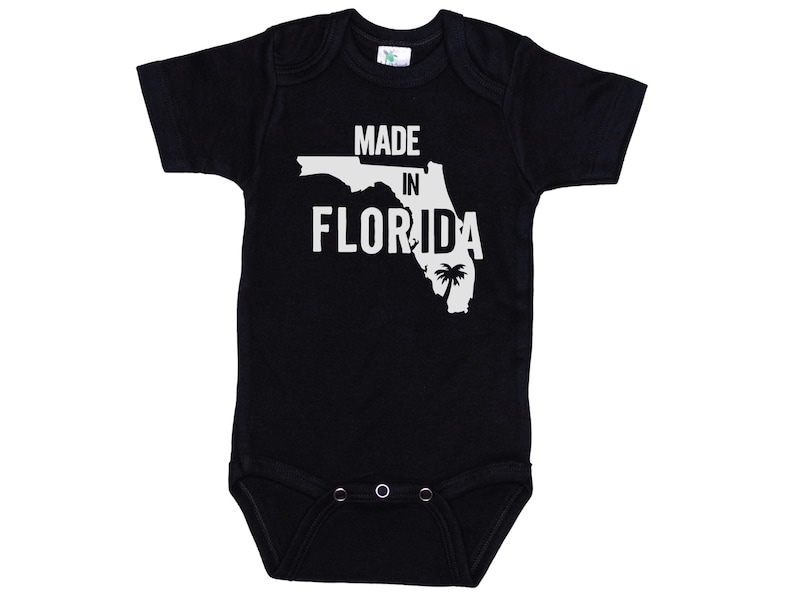 K&ouml;nnte beinhalten: Schwarzer Baby-Strampler mit wei&szlig;em Text "Made in Florida" und einer wei&szlig;en Umrandung des Bundesstaates Florida mit einer Palme.