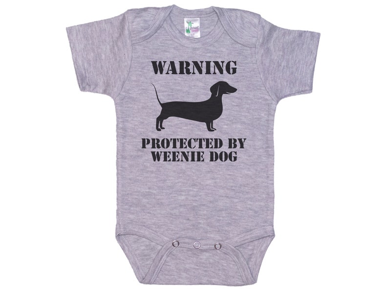 May include: Gray baby onesie with a black silhouette of a dachshund and the text "WARNING PROTECTED BY WEENIE DOG"