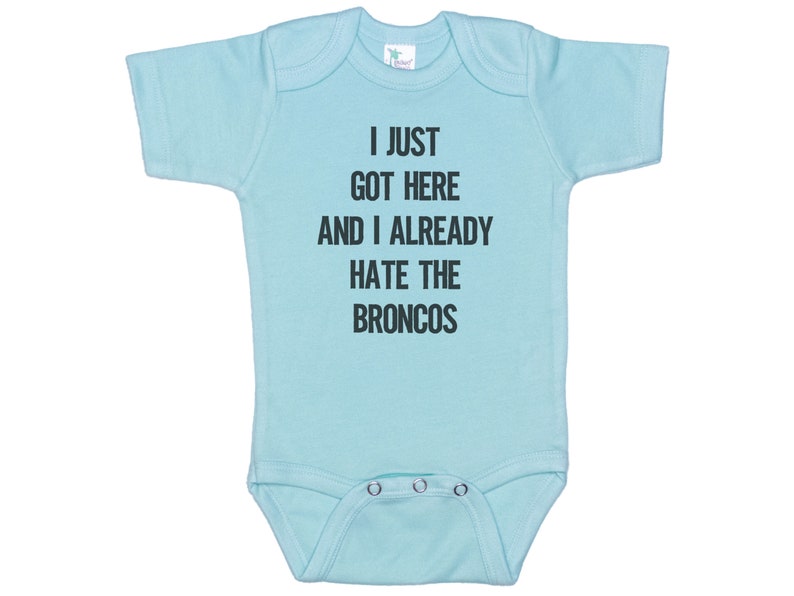 May include: A light blue baby onesie with the text "I just got here and I already hate the Broncos" printed in black.