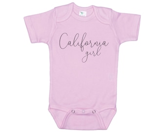 Könnte beinhalten: Ein rosa Baby-Strampler mit dem Schriftzug "California girl" in schwarzer Schrift.