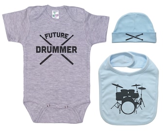 Könnte beinhalten: Ein grauer Baby-Body, eine hellblaue Lätzchen und eine hellblaue Mütze. Der Body hat den Text "FUTURE DRUMMER" mit Drumsticks. Das Lätzchen zeigt eine Schlagzeug-Silhouette. Die Mütze hat Drumsticks.