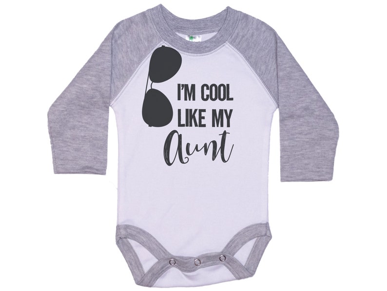 May include: A white and gray long-sleeve baby bodysuit with a black graphic of sunglasses and the text "I'm cool like my Aunt".