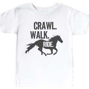 May include: White t-shirt with a black silhouette of a horse running and the text "Crawl. Walk. Ride."