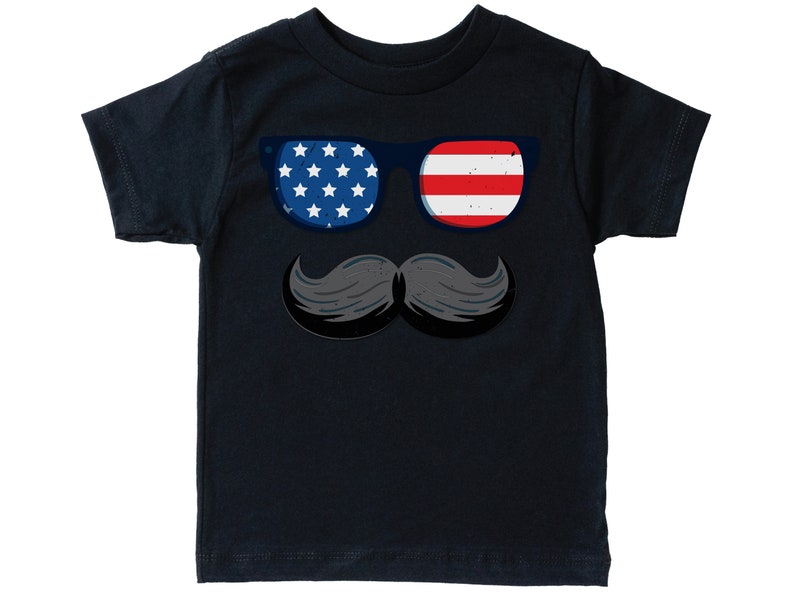 May include: A navy blue t-shirt with a graphic of sunglasses and a moustache. The sunglasses have a blue frame, with one lens showing white stars on a blue background and the other with red and white stripes, representing the American flag.