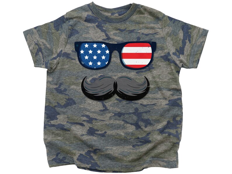 May include: A camouflage-patterned t-shirt with a graphic of sunglasses displaying the American flag and a black mustache. The sunglasses have a blue frame. The shirt is a youth size.