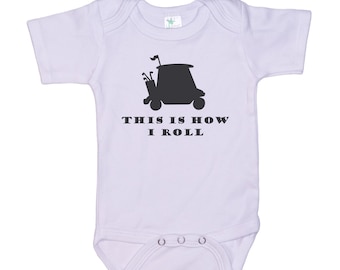 May include: White baby onesie with a black silhouette of a golf cart and the text "This is how I roll."