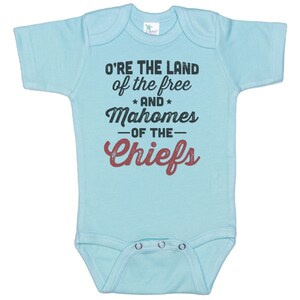 Pode incluir: Macac&atilde;o de beb&ecirc; azul claro com o texto "O're the land of the free *and* Mahomes -of the- Chiefs" em preto e vermelho.