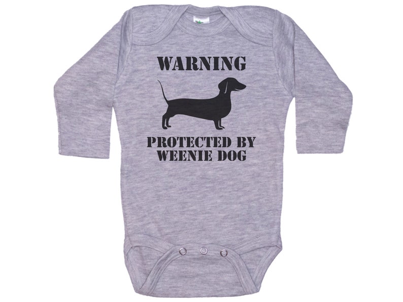 May include: Gray long-sleeve baby onesie with black text that reads "WARNING PROTECTED BY WEENIE DOG" and a black silhouette of a dachshund.