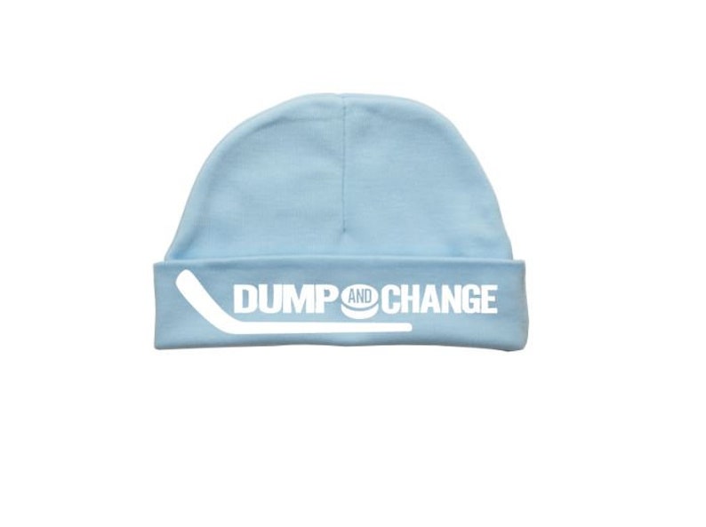 May include: A light blue baby beanie with the text "DUMP AND CHANGE" in white, with a white hockey stick graphic.