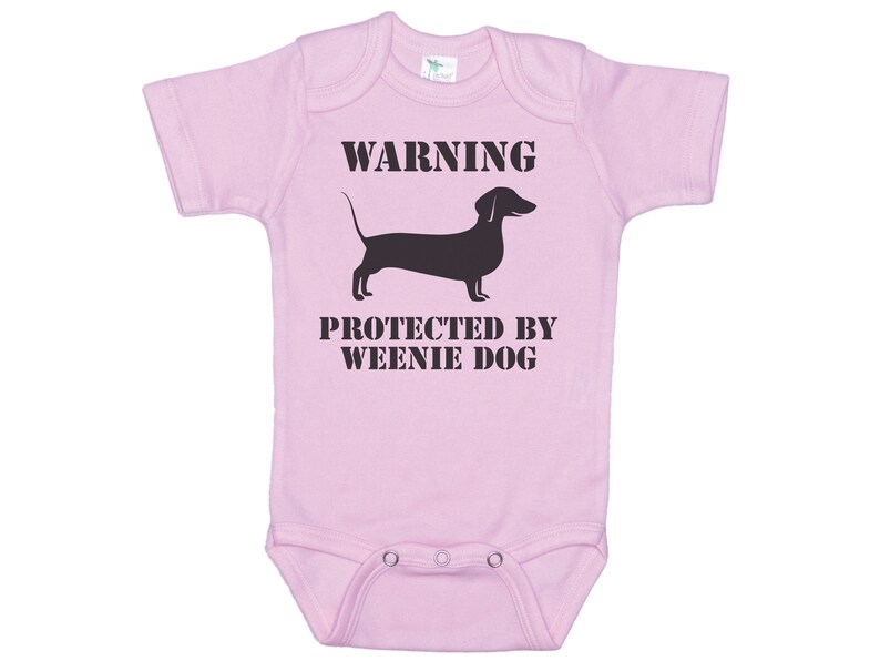 May include: Pink baby onesie with a black dachshund silhouette and the text "WARNING PROTECTED BY WEENIE DOG".
