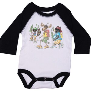 May include: White long-sleeve baby onesie with black raglan sleeves. The onesie features a graphic of a moose, a raccoon, and a bear wearing backpacks and hiking.
