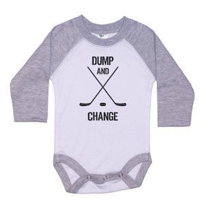 May include: A white and gray long-sleeve baby onesie with a hockey stick graphic and the text "DUMP AND CHANGE".