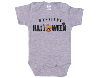 May include: Gray short-sleeved baby onesie with the text "MY FIRST HALLOWEEN" in black with a black silhouette of a pumpkin and hands.