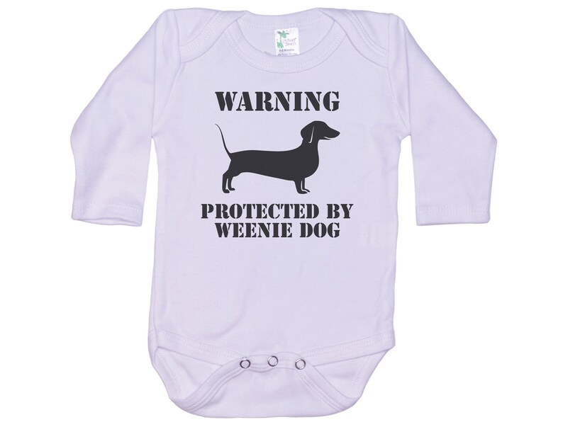 May include: White long-sleeve baby onesie with black text that reads "WARNING PROTECTED BY WEENIE DOG" and a black silhouette of a dachshund.