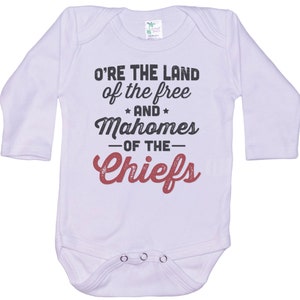 Pode incluir: Macac&atilde;o branco de manga comprida para beb&ecirc; com o texto "O're the land of the free and Mahomes -of the- Chiefs" em preto e vermelho.